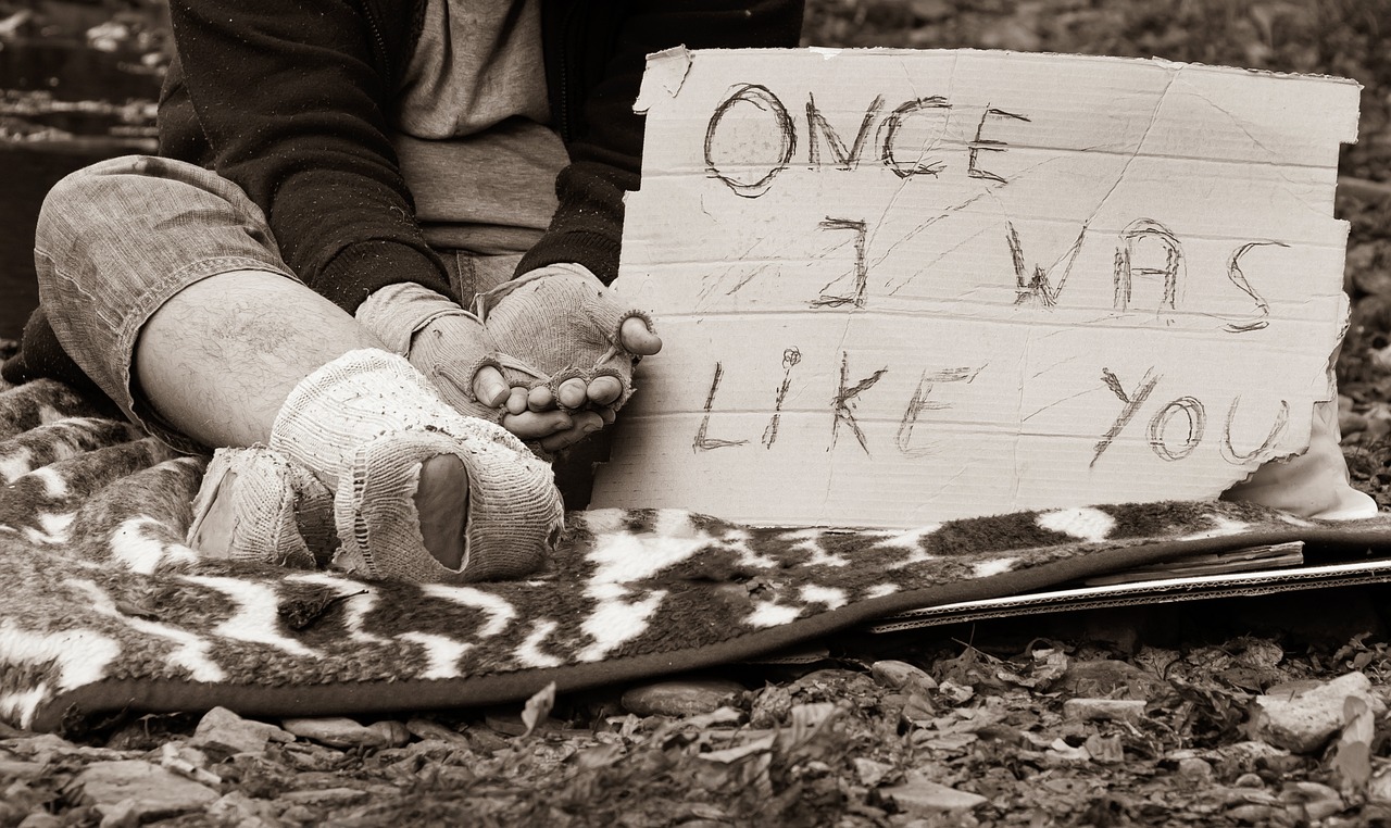 "Once I was like you" reads a sign next to a homeless person begging